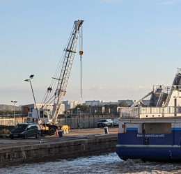 A mobile crane on the dockside beside a docked vessel.