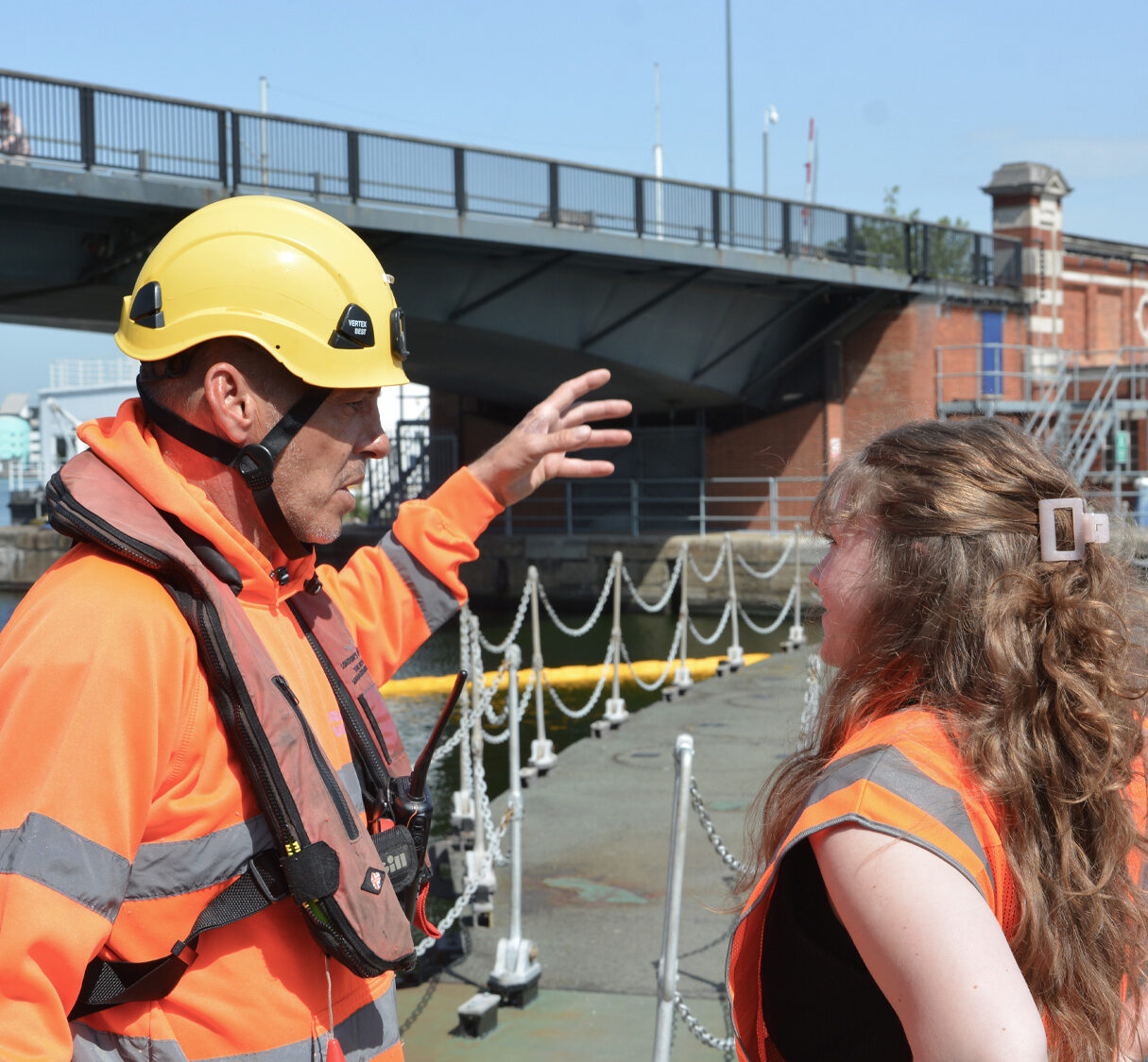 Two team members in high-vis on the dock talking. One is in a hardhat.