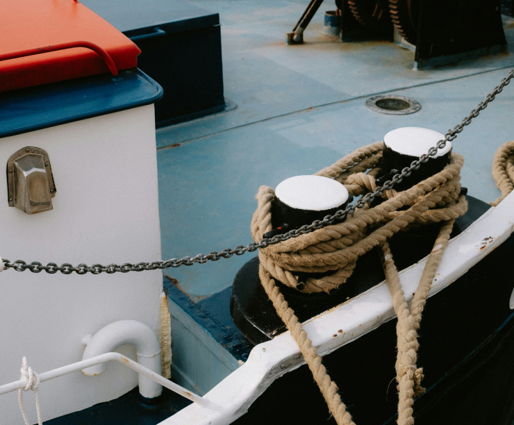 Close-up of mooring ropes and chains on a boat's deck.