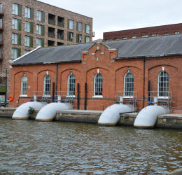 Large white dock pumps beside a red brick pump house.