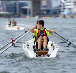 A young rower on the dock, other rowers behind.